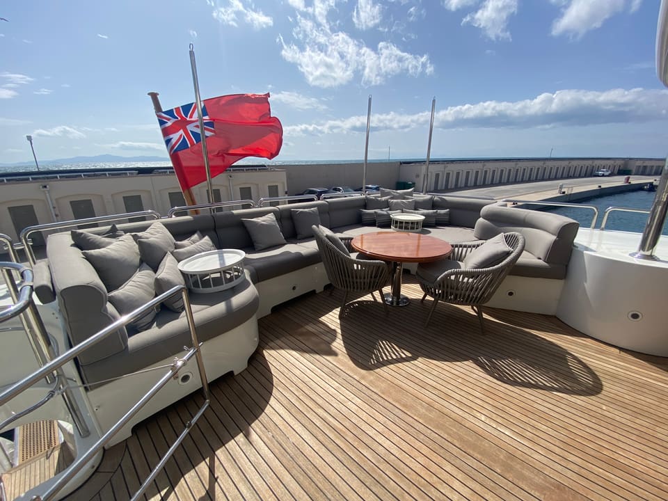 2003 Benetti Classic 115 – aft deck with wraparound sofa, round teak table, rattan chairs and teak decking