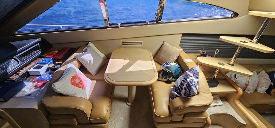 2005 Ferretti 530 – dinette with tan leather seating, folding table and large panoramic windows