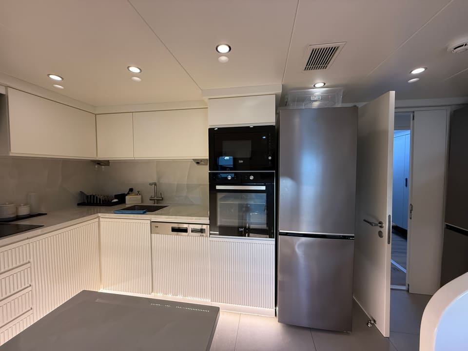 2023 Custom Laminated Motorsailer 41M – galley with white cabinetry, built-in oven and microwave, stainless fridge and dishwasher
