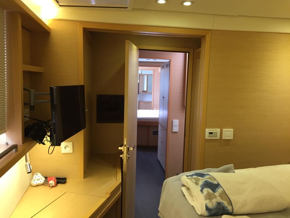 2015 Lagoon 560 S2 – duvara monte TV'li, makyaj masalı misafir kabini ve koridor ile banyoya açılan kapı