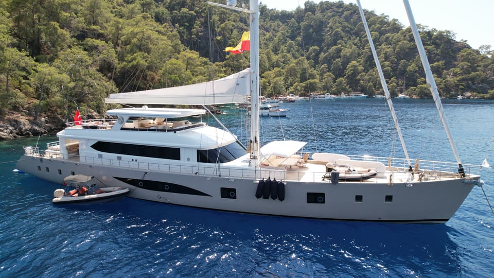 2023 Custom Laminated Motorsailer 41M – starboard side profile at anchor with twin masts, sun pads on deck and tender alongside