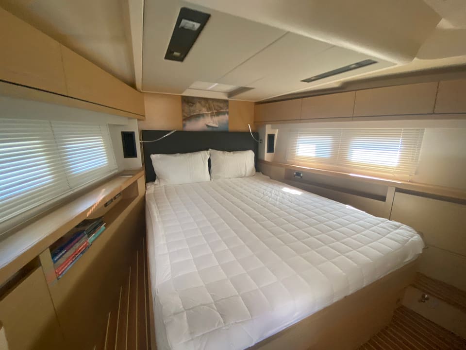 2018 Hanse 548 – cabin with island double bed, hull windows with blinds, light wood joinery and bookshelf