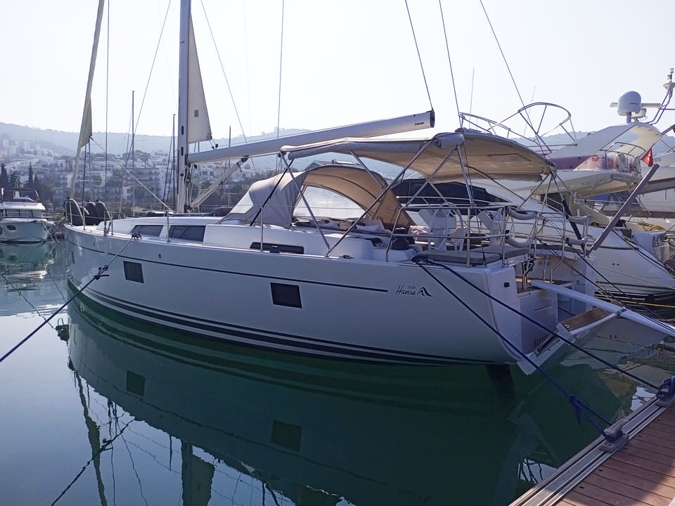 2022 Hanse 508 – white hull sailing yacht with bimini and sprayhood, moored stern-to with calm water reflections