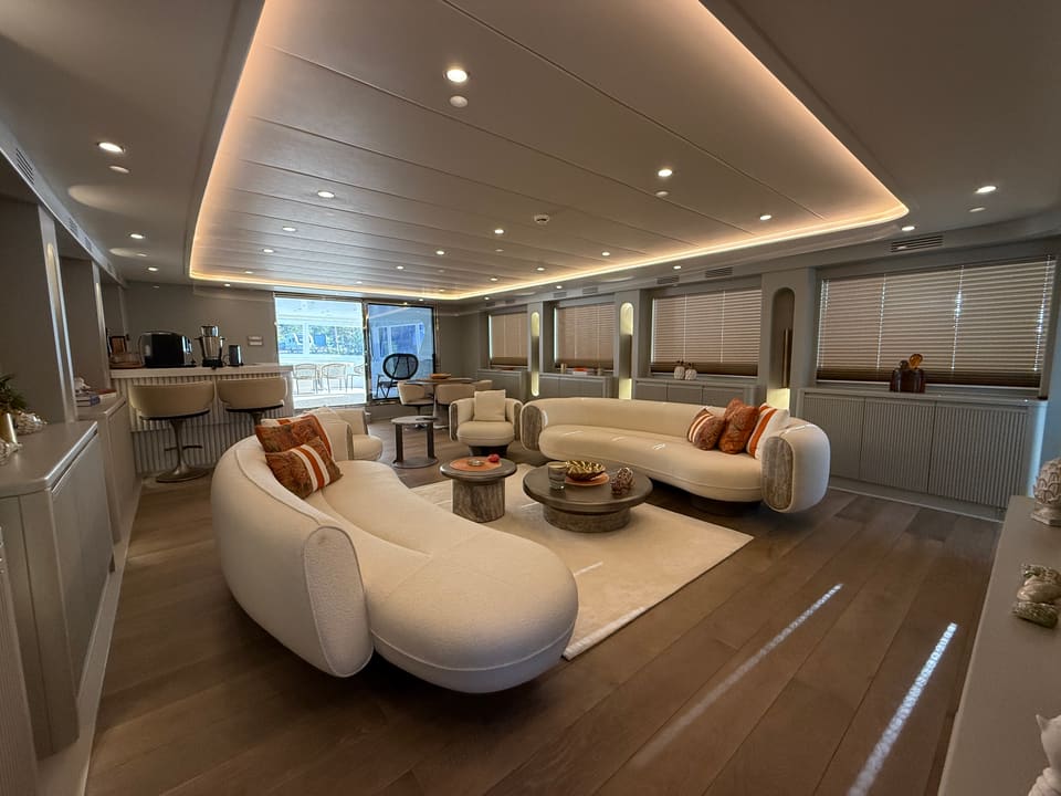 2023 Custom Laminated Motorsailer 41M – main saloon with curved cream sofas, coffee tables, wood floor and cove-lit ceiling