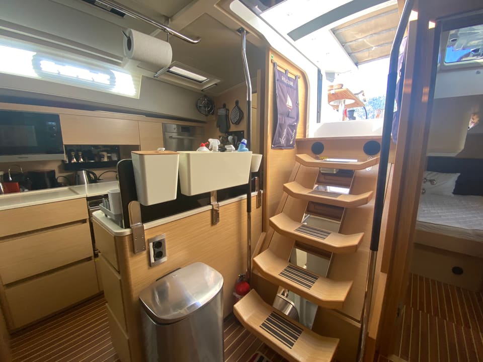 2018 Hanse 548 – galley with light wood cabinetry, stainless bin and companionway steps leading to the cockpit