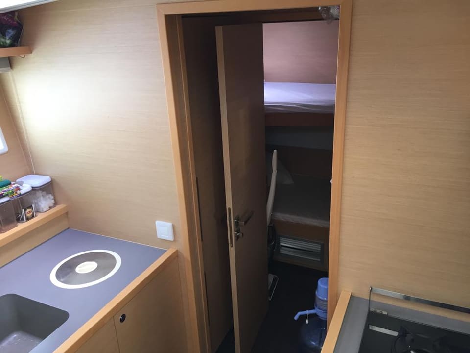 2015 Lagoon 560 S2 – mutfak köşesi, indüksiyon ocak ve ranzalı kabine açılan kapısıyla mürettebat bölümü