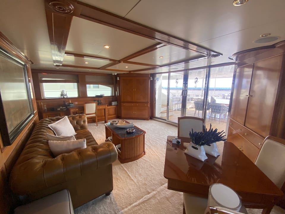 2003 Benetti Classic 115 – main saloon with leather Chesterfield sofa, wood paneling and glass doors to aft deck