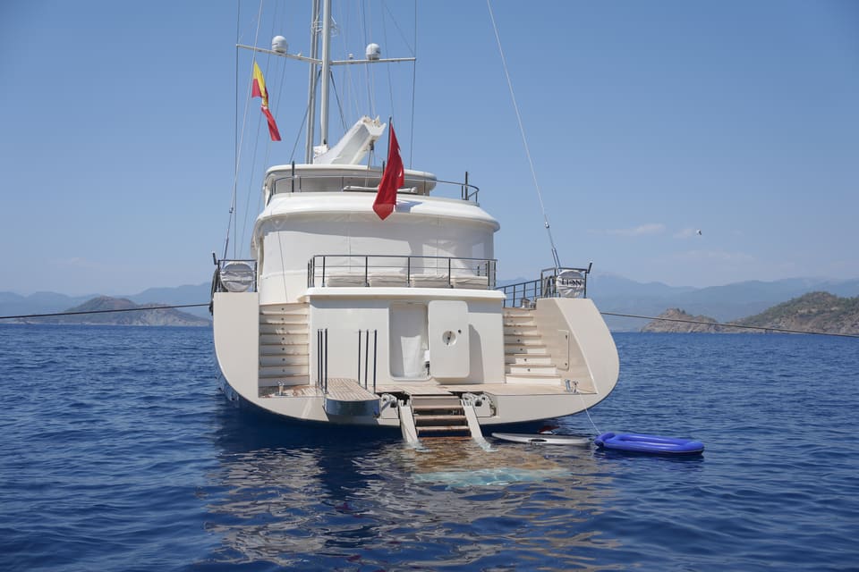 2023 Custom Laminated Motorsailer 41M – stern view with swim platform, twin stairs, aft deck and flags at anchor