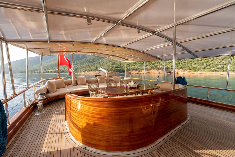 2009 Custom Ketch 31M – shaded aft deck with wraparound cushioned sofa, teak dining table and varnished wood bar under canopy