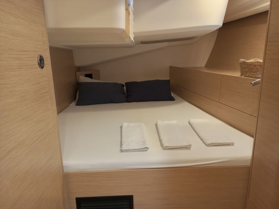 2022 Hanse 508 – çift kişilik yataklı misafir kabini, lacivert yastıklar, katlanmış havlular ve açık meşe ahşap işçiliği