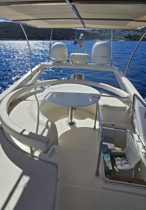 2005 Ferretti 530 – flybridge with curved bench seating, round table, bimini and radar domes overlooking the sea