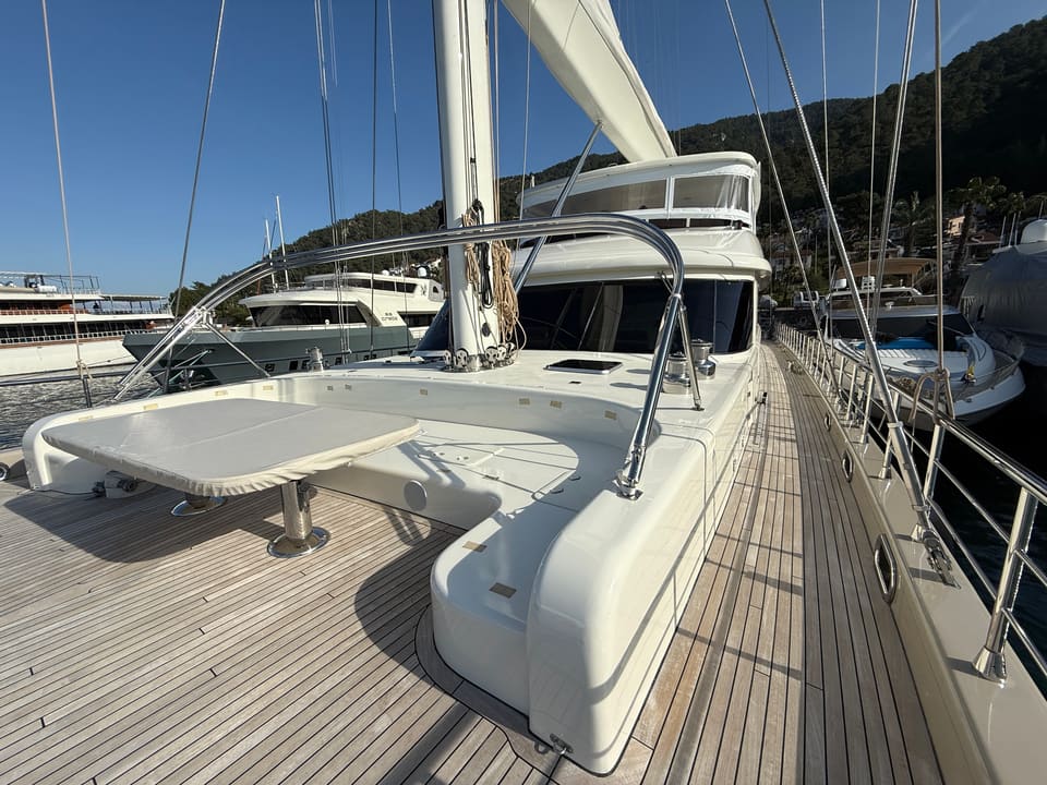 2023 Custom Laminated Motorsailer 41M – teak foredeck with cushioned seating, folding table and stainless steel bimini frame