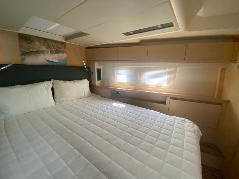 2018 Hanse 548 – cabin with double bed, white quilted bedding, light wood joinery, hull window and overhead hatch