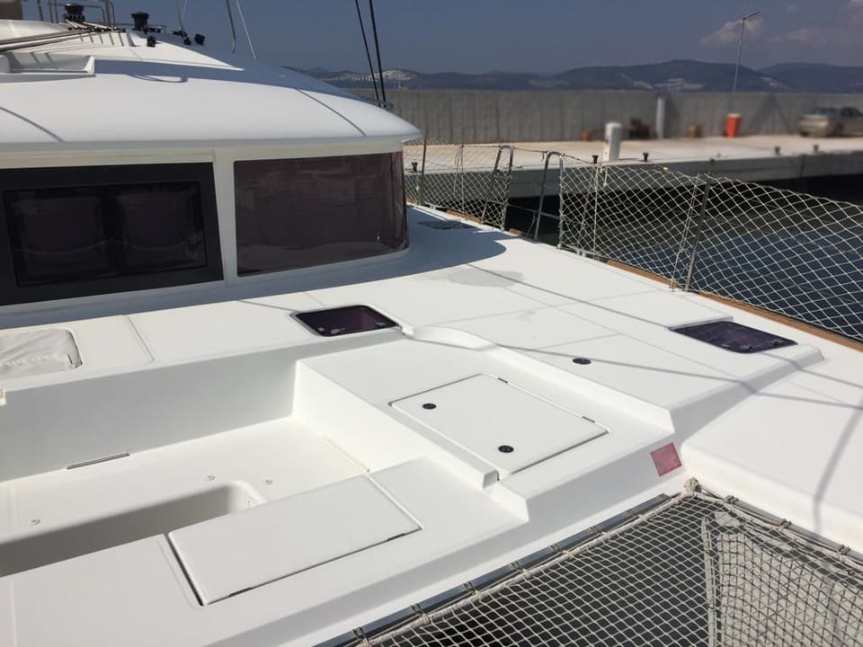 2015 Lagoon 560 S2 – salon camlarının önünde lombozlar, güverte dolapları ve trambolin fileli baş güverte