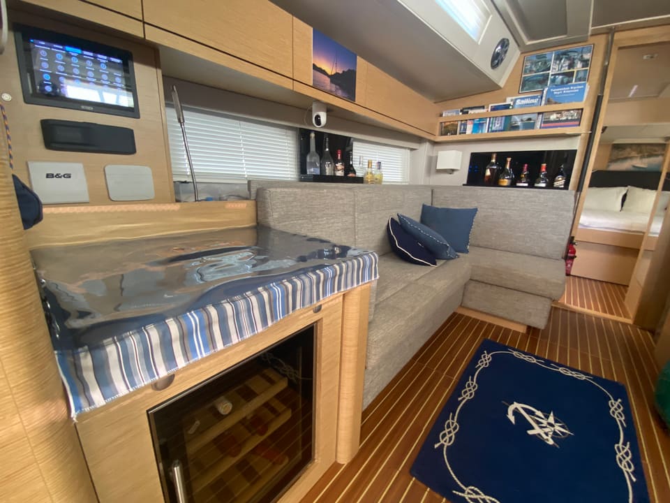 2018 Hanse 548 – saloon with L-shaped sofa, wine cooler, chart table display and teak floor