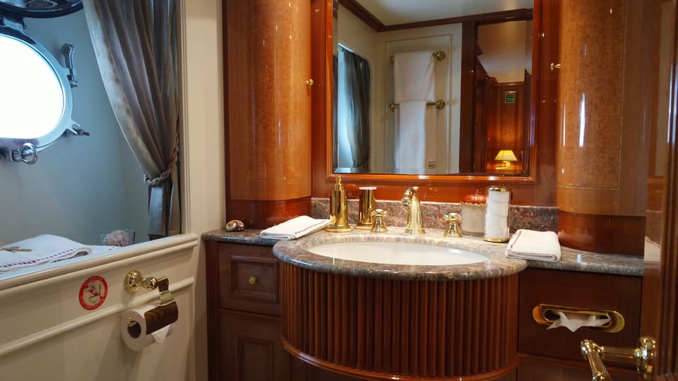 2003 Benetti Classic 115 – guest bathroom with granite vanity, gold fixtures, cherry wood cabinetry and porthole