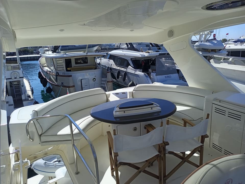 2009 Silverton 52 Ovation – beyaz U oturma grubu, lacivert masa, katlanır sandalyeler ve hardtop gölgelikli flybridge