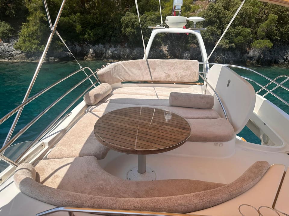 2002 Prestige 46 – flybridge with U-shaped beige seating, round teak table and radar arch