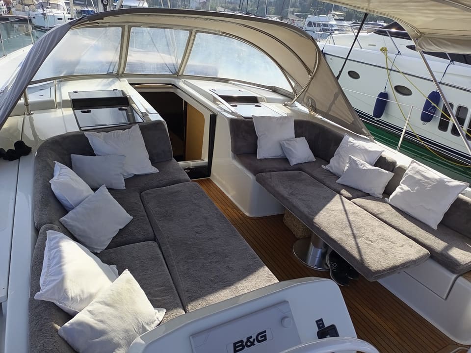 2022 Hanse 508 – cockpit with grey cushioned seating, folding tables and bimini, B&G helm display in foreground