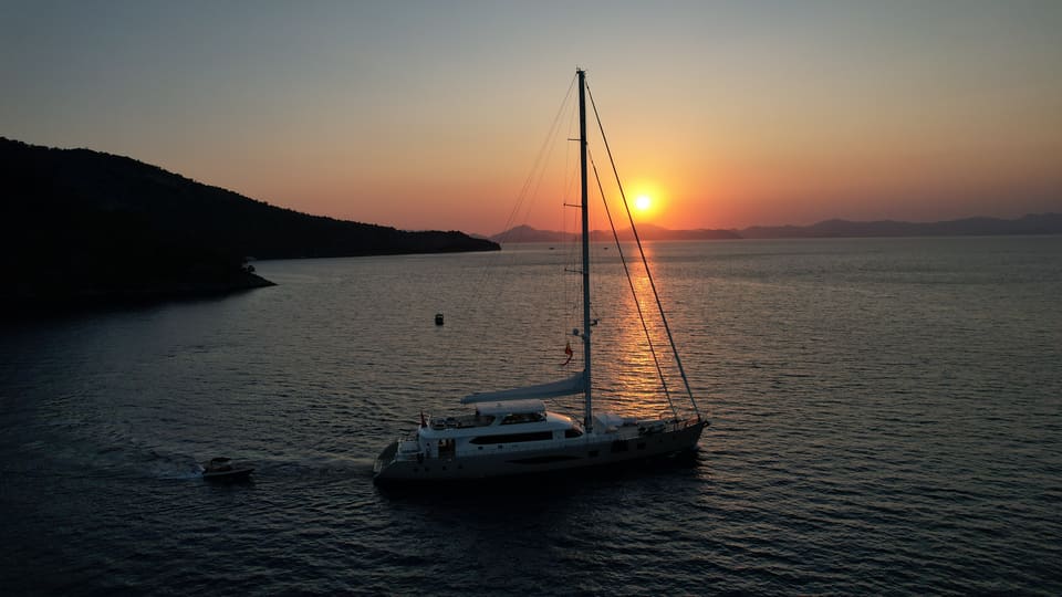 2023 Custom Laminated Motorsailer 41M – aerial view under way at sunset with tall mast and tender alongside