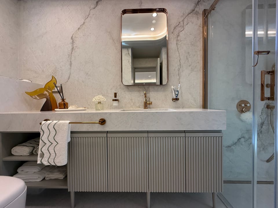 2023 Custom Laminated Motorsailer 41M – marble bathroom with fluted vanity, brass fittings, framed mirror and glass shower