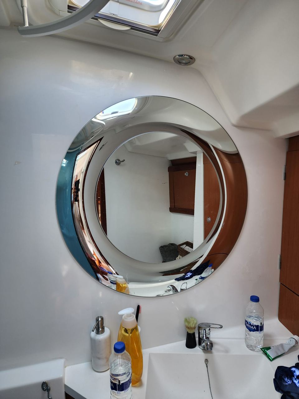 2009 Beneteau Oceanis 54 – yuvarlak aynalı, beyaz lavabolu ve tavan kaportalı banyo