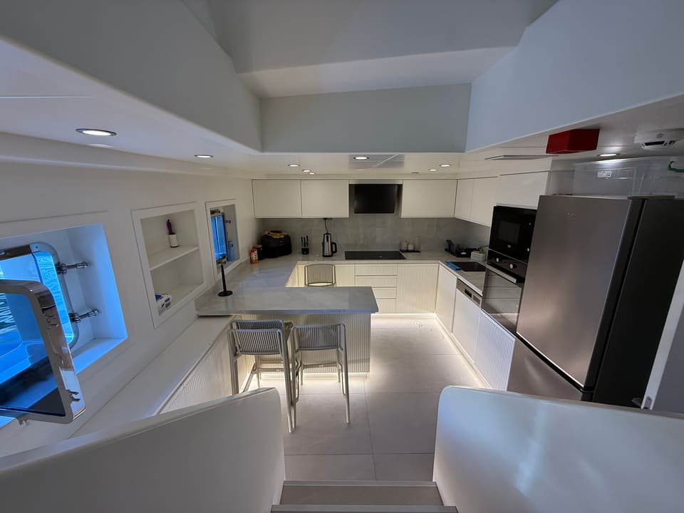 2023 Custom Laminated Motorsailer 41M – white galley with breakfast bar, stools, stainless fridge and portholes