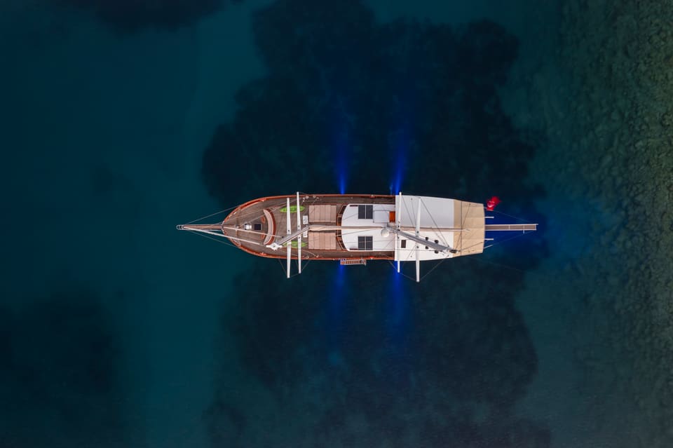 2009 Custom Ketch 31M – overhead aerial view of the wooden ketch at anchor in clear turquoise water with underwater lights