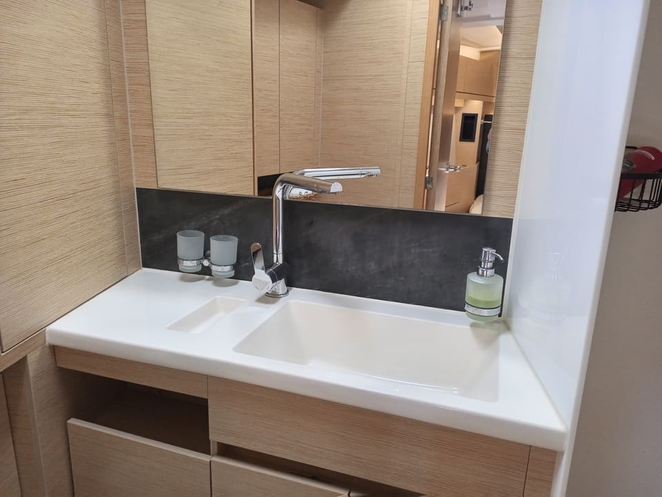 2022 Hanse 508 – beyaz entegre lavabolu banyo tezgahı, krom batarya, aynalı dolaplar ve ahşap görünümlü dolaplar