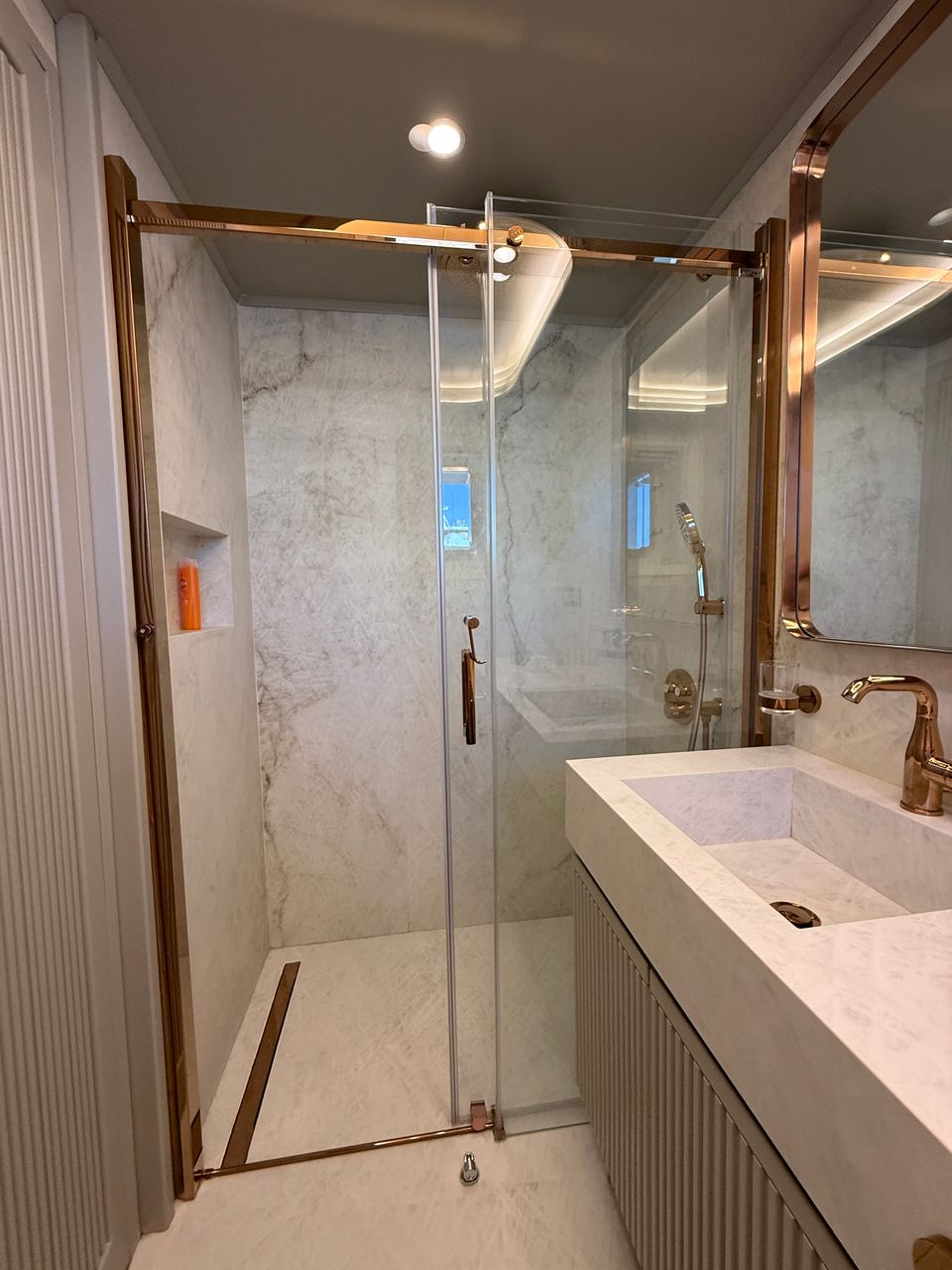 2023 Custom Laminated Motorsailer 41M – marble bathroom with glass shower, rose gold fittings and stone vanity sink