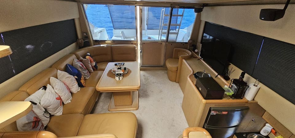 2005 Ferretti 530 – saloon with L-shaped cream leather sofa, coffee table, TV and galley counter leading to aft deck