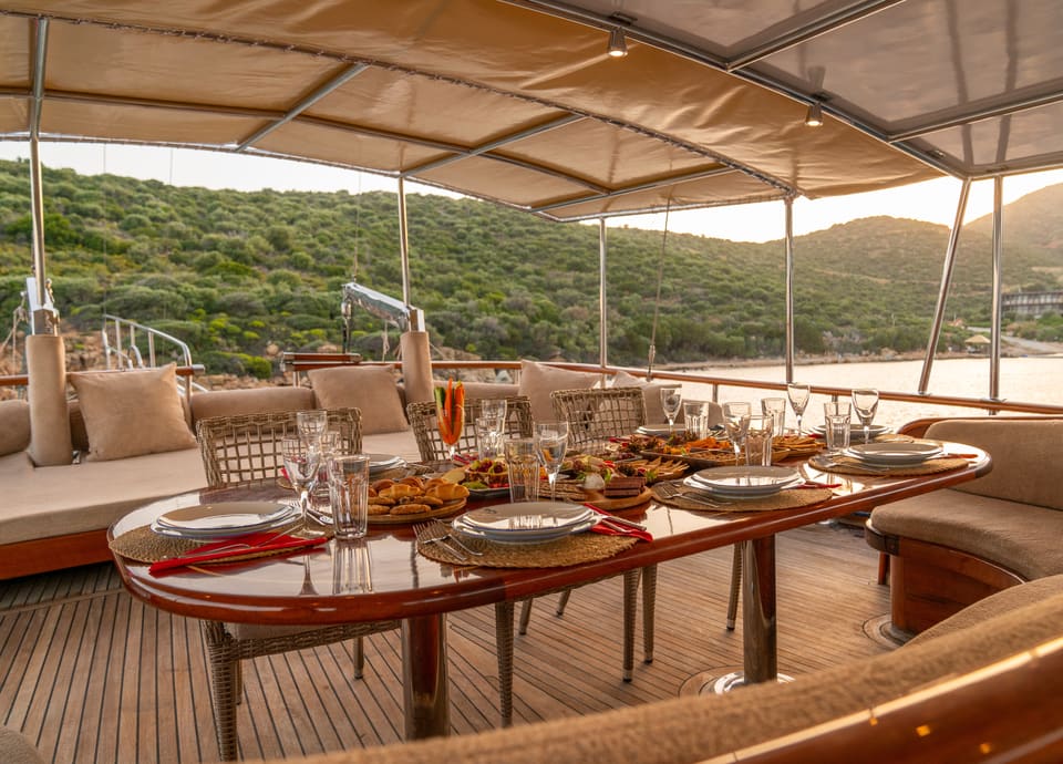 2009 Custom Ketch 31M – shaded aft deck with set dining table, wicker chairs and cushioned seating