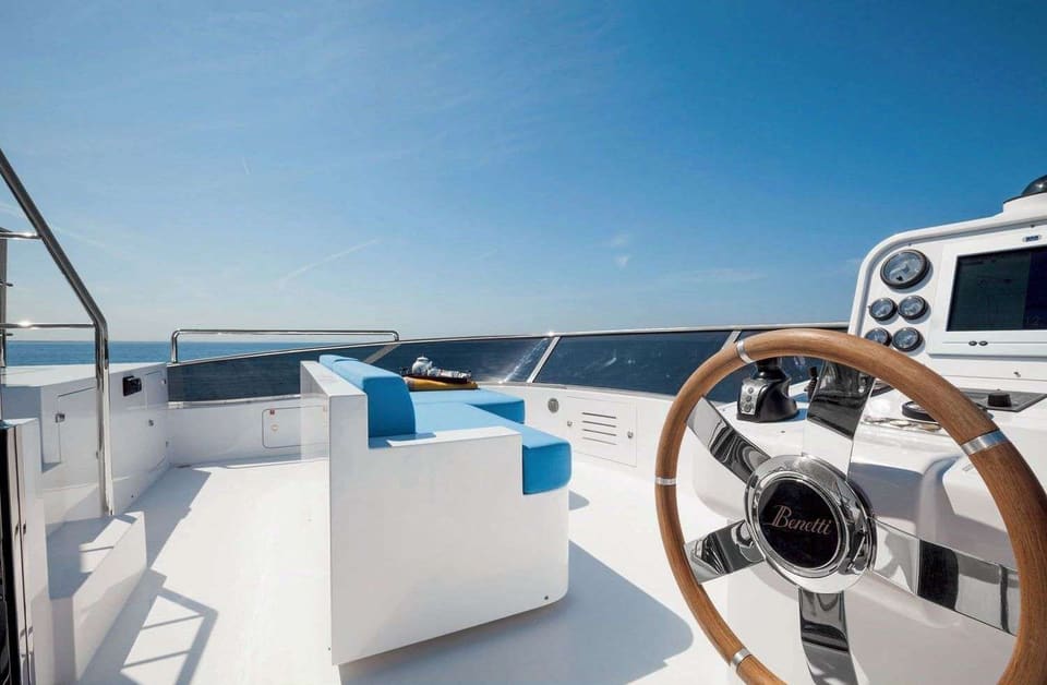 2016 Benetti Tradition Supreme 108 – flybridge dümen istasyonu, ahşap dümen simidi, gösterge paneli ve mavi minderli oturma alanı
