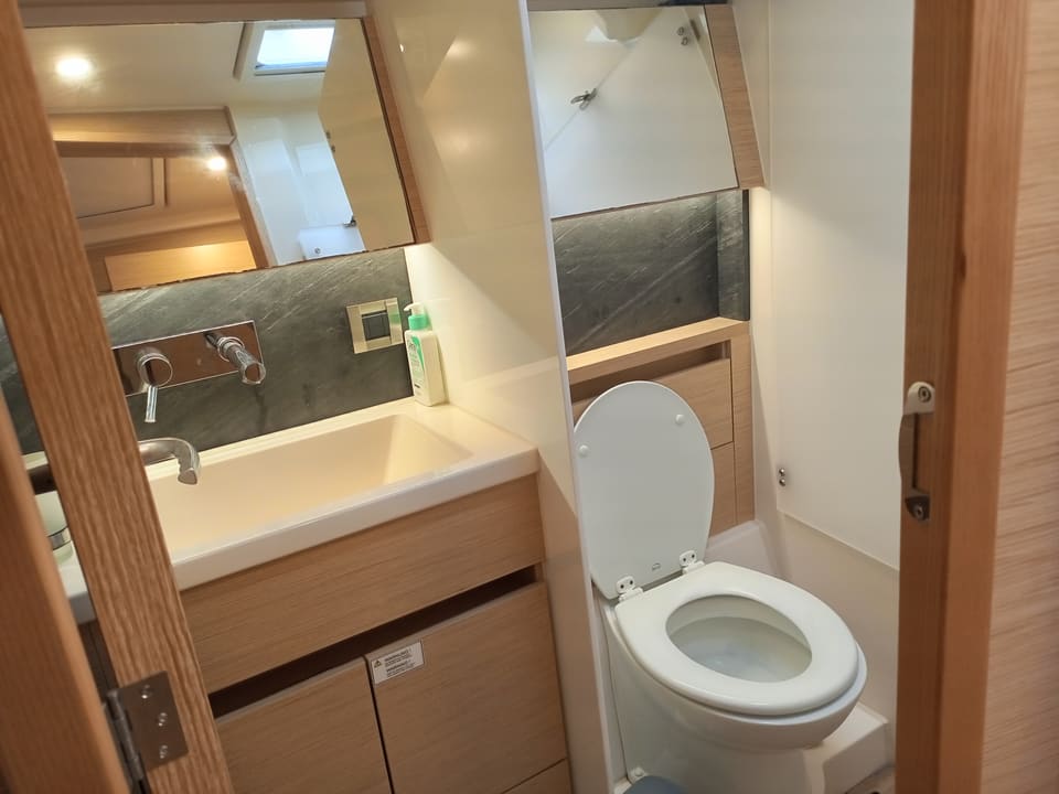 2022 Hanse 508 – deniz tipi tuvalet, lavabolu dolap, aynalı dolaplar ve açık meşe ahşap işçiliğine sahip banyo