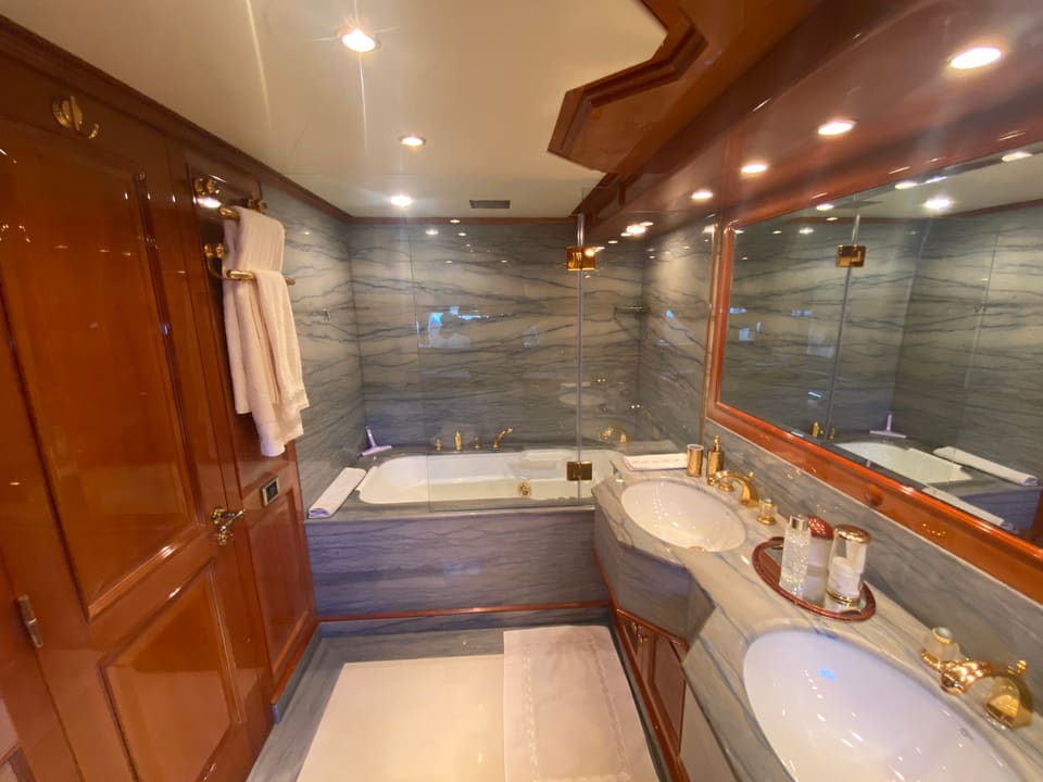 2003 Benetti Classic 115 – marble bathroom with bathtub, twin sinks, gold fixtures and glossy wood cabinetry