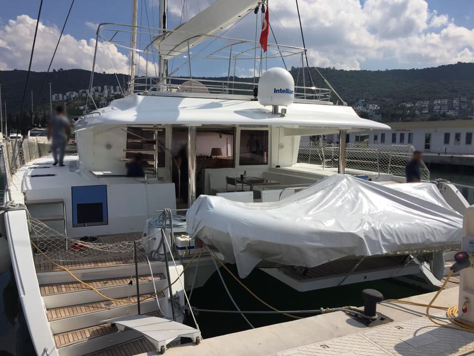 2015 Lagoon 560 S2 – kıç güverte, davitte örtülü bot, biniş basamakları ve salona açılan görünüm