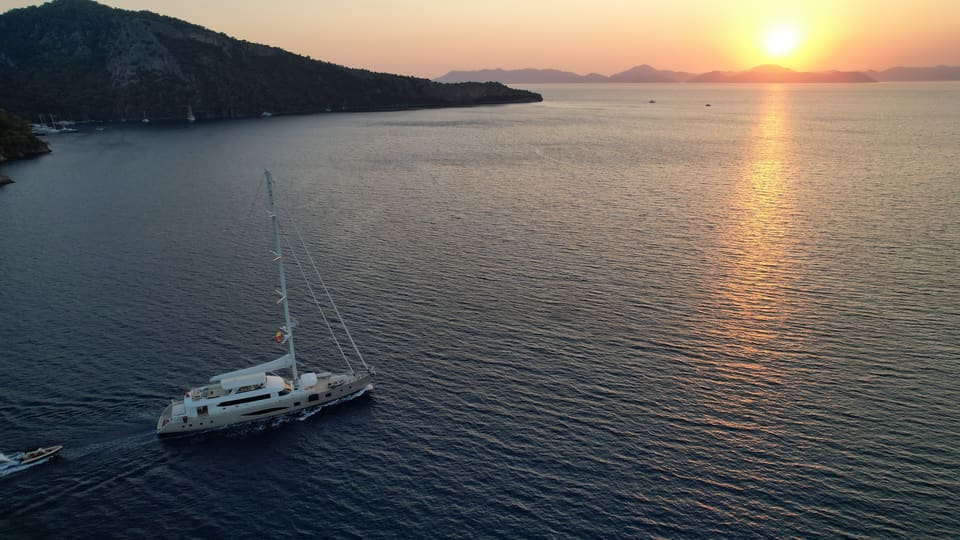 2023 Custom Laminated Motorsailer 41M – aerial view under sail at sunset with tender alongside on calm sea