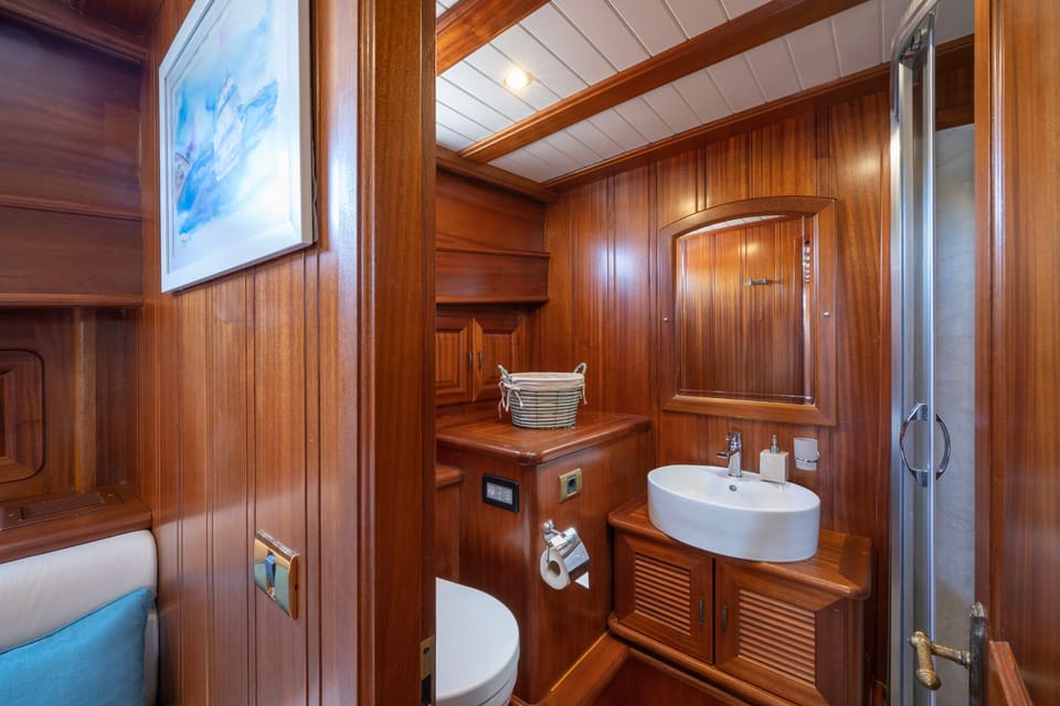 2009 Custom Ketch 31M – teak-panelled bathroom with vessel sink, louvred vanity, toilet and glass shower