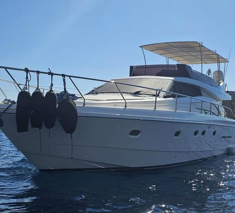 2005 Ferretti 530 – white hull from the bow with fenders, flybridge bimini and calm blue sea