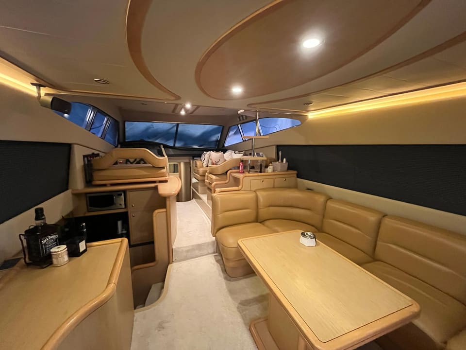 2005 Ferretti 530 – saloon with beige leather seating, dining table, bar unit and panoramic windows