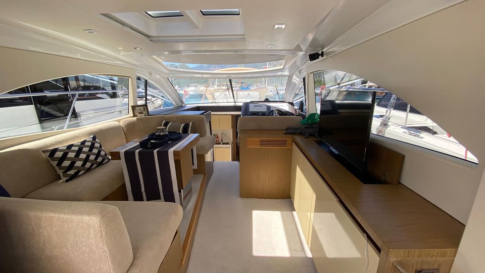 2014 Beneteau Gran Turismo 49 – L koltuklu salon, açılır TV, meşe dolaplar ve ileride dümen mevkii görünümü