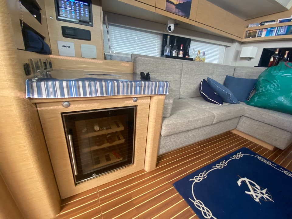 2018 Hanse 548 – saloon with L-shaped grey sofa, wine cooler cabinet and teak-style sole