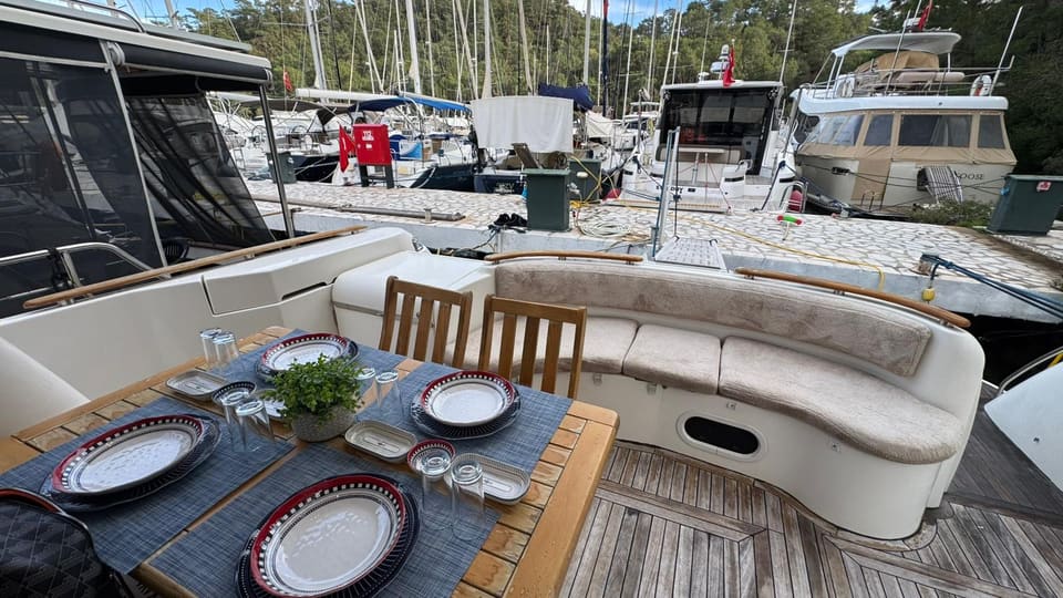 2002 Prestige 46 – aft deck with teak dining table set for lunch and cream U-shaped seating