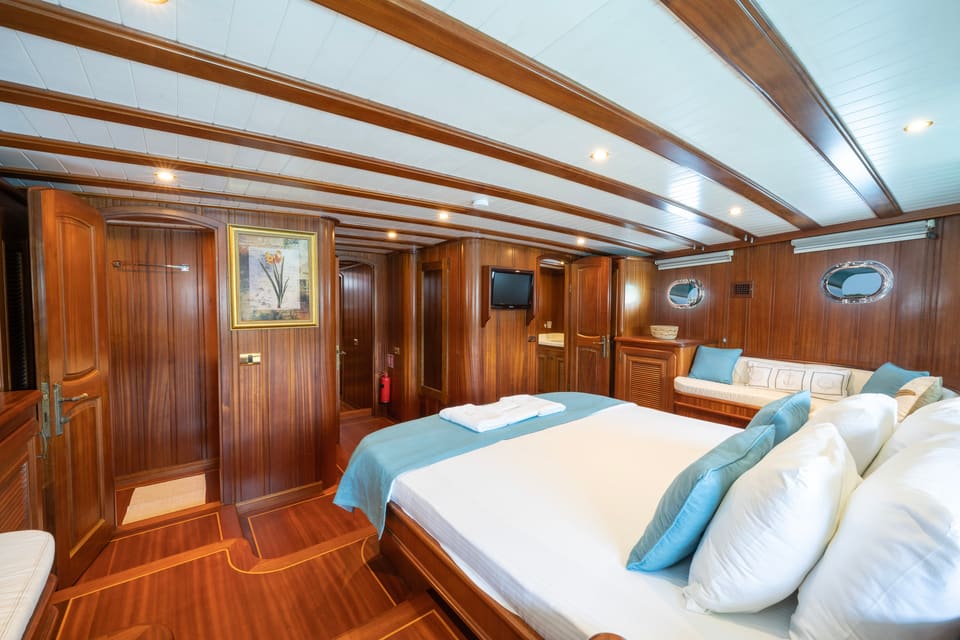 2009 Custom Ketch 31M – master cabin with double bed, teak paneling, sofa, portholes and TV
