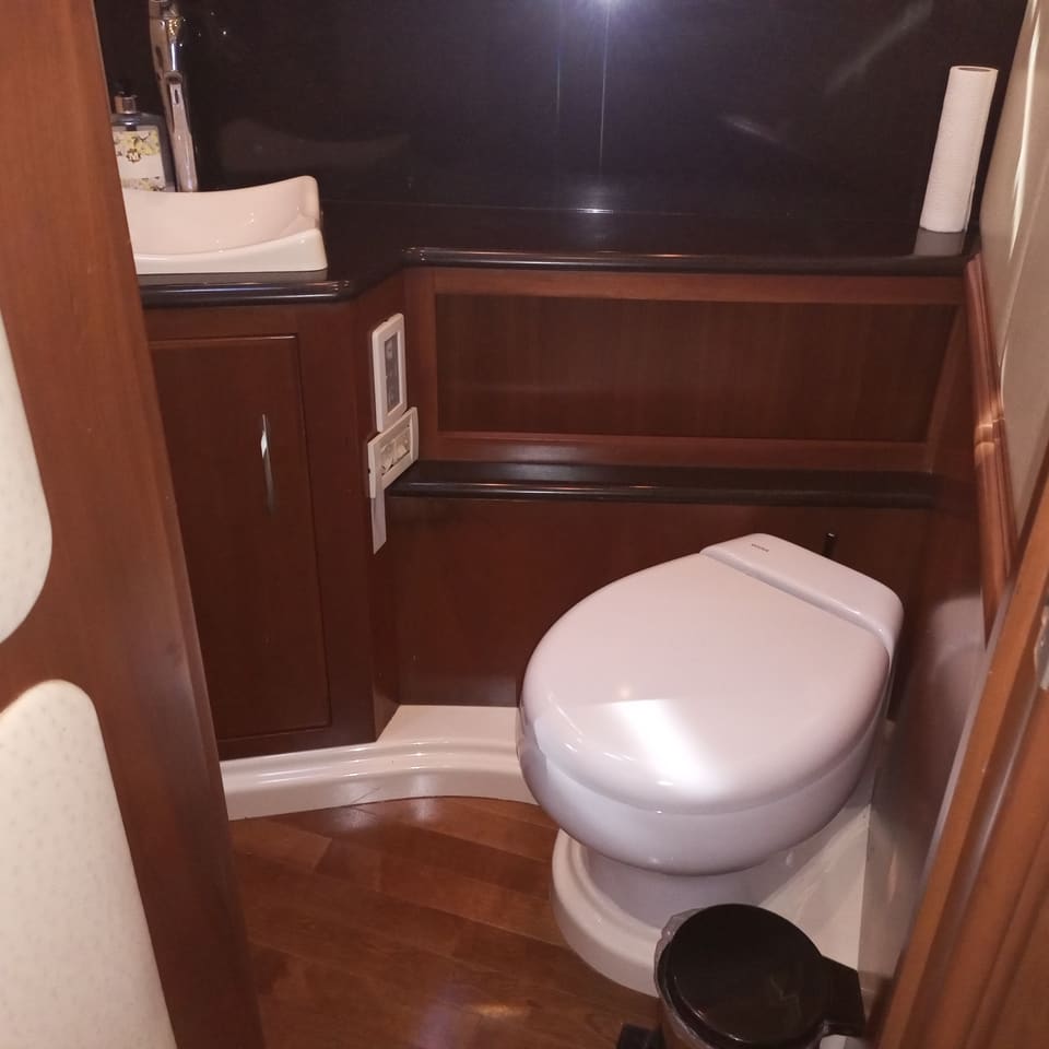 2009 Silverton 52 Ovation – deniz tipi klozet, kiraz ağacı dolaplar, tezgah üstü lavabo ve ahşap zeminli banyo