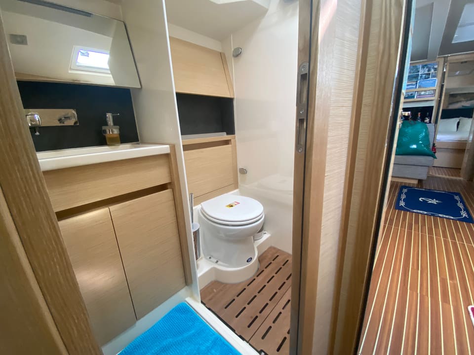 2018 Hanse 548 – bathroom with marine toilet, vanity sink, teak shower grating and light wood cabinetry
