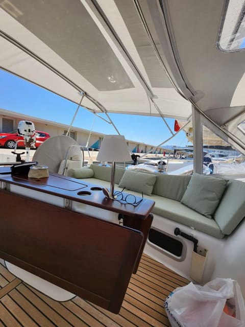 2009 Beneteau Oceanis 54 – bimini gölgeli kokpit, adaçayı yeşili minderli oturma alanı ve katlanır tik masa