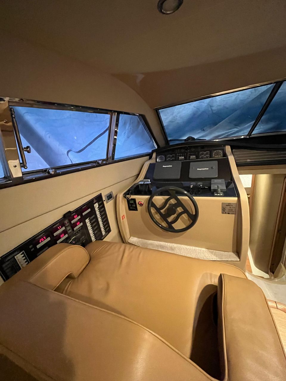 2005 Ferretti 530 – interior lower helm station with tan leather seat, wheel, chartplotters and switch panel