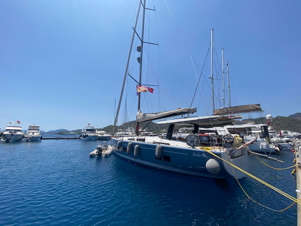 2018 Hanse 548 – navy blue hull with fenders, tall mast and cockpit bimini, moored stern-to