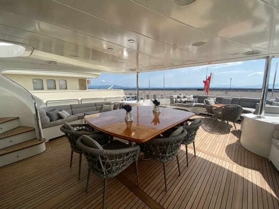 2003 Benetti Classic 115 – covered aft deck with teak dining table, woven chairs and lounge seating